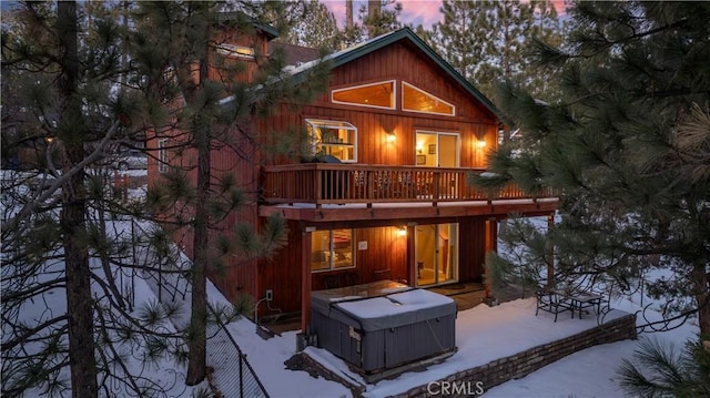 back of property at dusk featuring a deck, a hot tub, and a patio