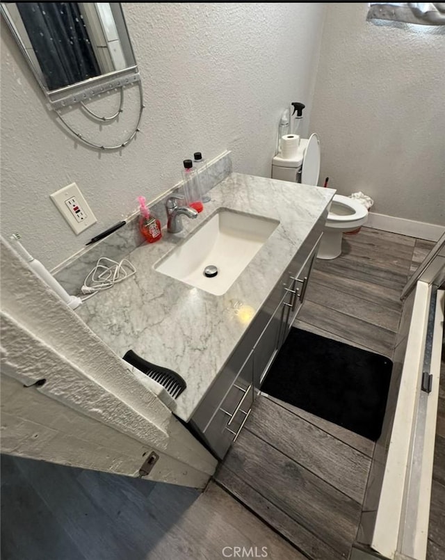 bathroom with toilet, vanity, and a textured wall