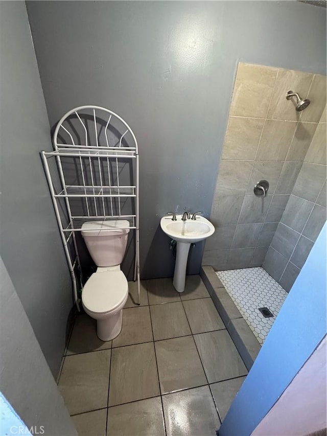 bathroom featuring tile patterned floors, toilet, and a stall shower