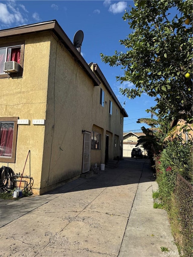 view of side of property with stucco siding, fence, cooling unit, and a patio area