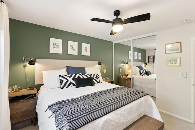 carpeted bedroom with a closet, baseboards, and a ceiling fan