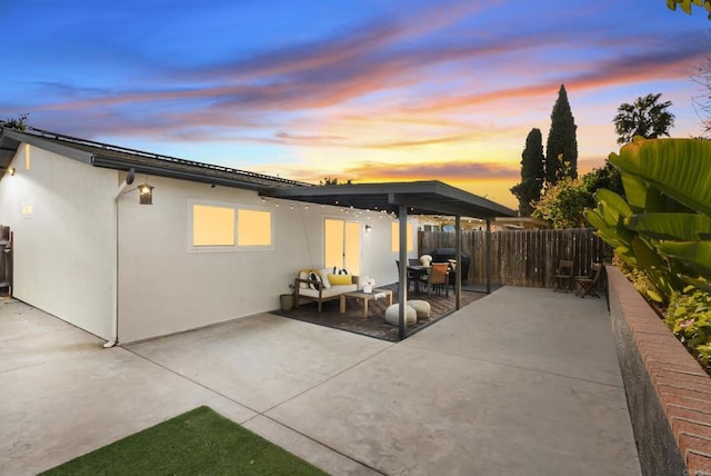 back of property at dusk with a patio area, fence, and stucco siding