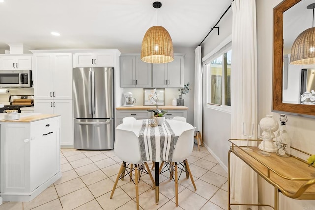 kitchen featuring light tile patterned floors, stainless steel appliances, hanging light fixtures, and light countertops