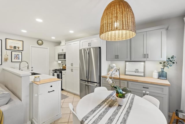 kitchen with light tile patterned floors, recessed lighting, a sink, stainless steel appliances, and built in desk