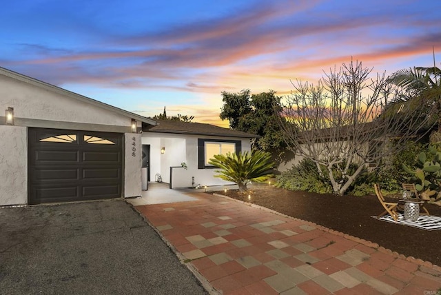 view of front of property with aphalt driveway, stucco siding, and a garage