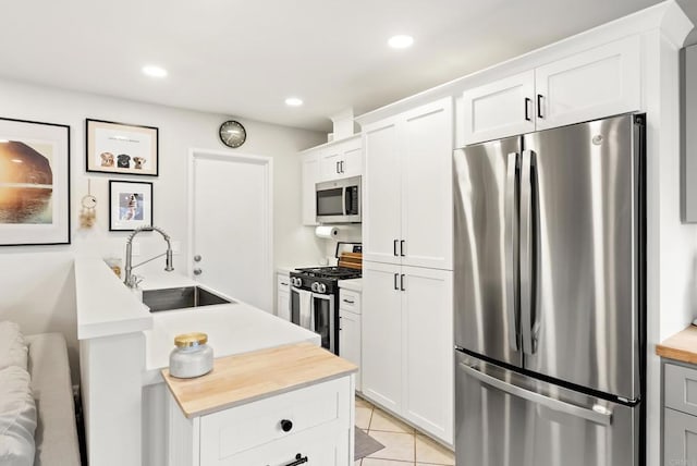 kitchen featuring a sink, recessed lighting, appliances with stainless steel finishes, light tile patterned flooring, and white cabinets