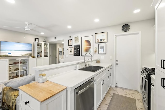 kitchen featuring a sink, stainless steel appliances, a peninsula, white cabinets, and light tile patterned floors