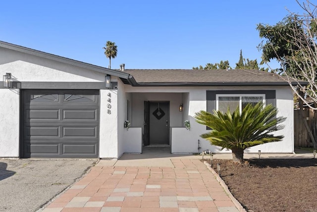 ranch-style home with stucco siding, an attached garage, and a shingled roof