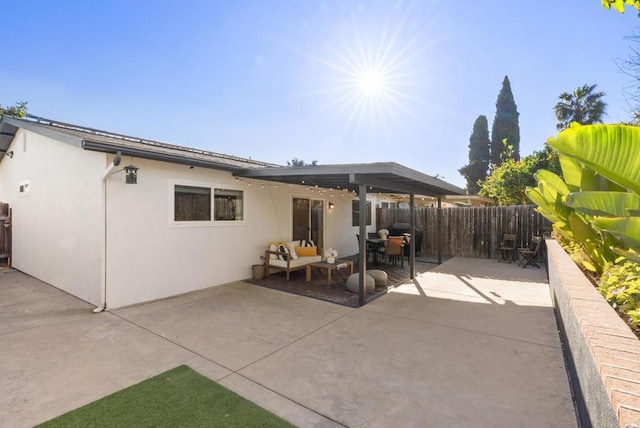 rear view of property with stucco siding, fence, and a patio area