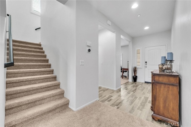 interior space featuring recessed lighting, light wood-style flooring, baseboards, and stairs