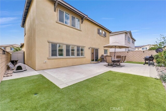 rear view of house with fence, a patio, and stucco siding