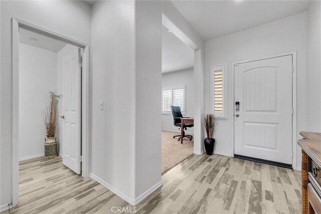 foyer entrance featuring light wood-style flooring and baseboards