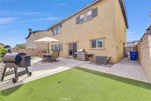 rear view of house featuring fence, central AC unit, and stucco siding