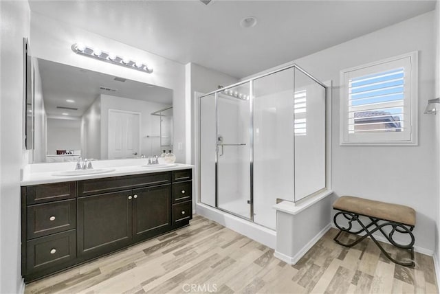 full bathroom featuring a stall shower, baseboards, wood finished floors, and vanity