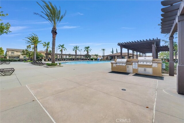 pool with area for grilling, a patio, an outdoor kitchen, and a pergola