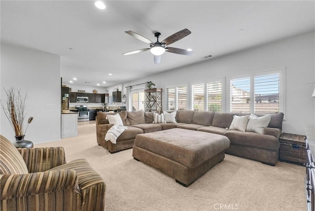 living area with a ceiling fan, a wealth of natural light, light colored carpet, and recessed lighting