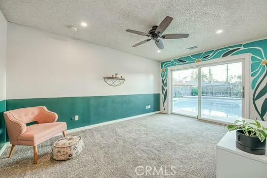 living area featuring a textured ceiling, visible vents, carpet, and a ceiling fan