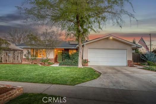 view of front of home with driveway, an attached garage, roof mounted solar panels, a front lawn, and stucco siding