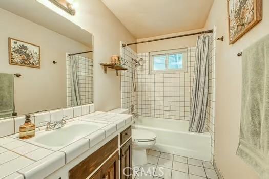 bathroom featuring shower / tub combo, vanity, toilet, and tile patterned floors