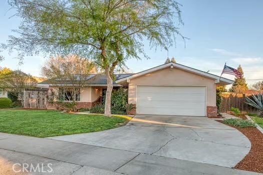 ranch-style home with an attached garage, fence, driveway, stucco siding, and a front yard