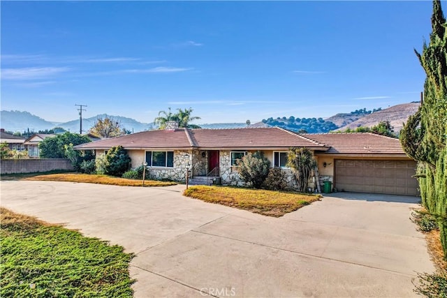 single story home featuring stucco siding, a mountain view, a garage, stone siding, and driveway