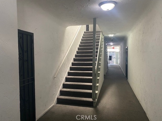 stairs with a textured ceiling and a textured wall