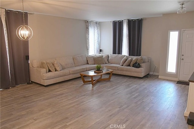 living room featuring an inviting chandelier, baseboards, and wood finished floors