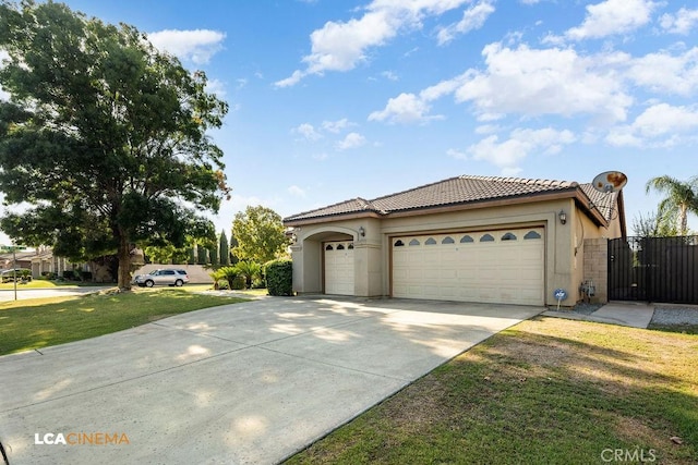 mediterranean / spanish-style house with concrete driveway, stucco siding, a tile roof, an attached garage, and a front yard