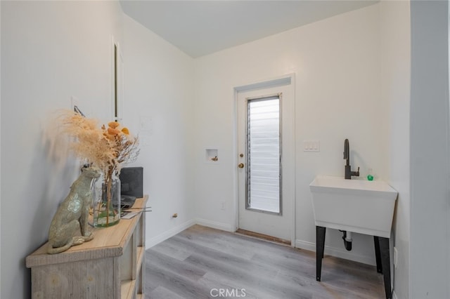 doorway featuring light wood-style floors and baseboards