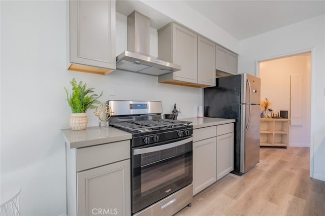 kitchen featuring baseboards, light wood-style floors, light countertops, appliances with stainless steel finishes, and wall chimney exhaust hood