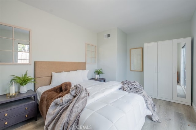 bedroom featuring light wood-type flooring, visible vents, and a closet