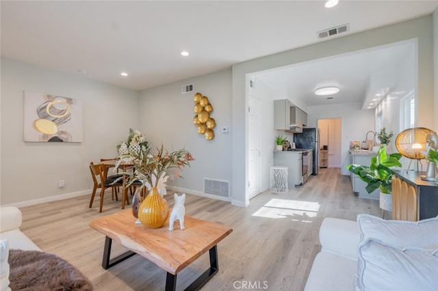 living area featuring light wood finished floors, visible vents, and recessed lighting