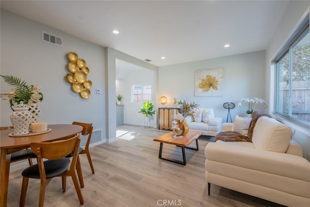 living area featuring light wood-style floors, visible vents, and plenty of natural light