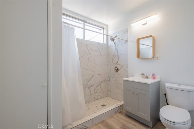 bathroom featuring vanity, a shower stall, toilet, and wood finished floors