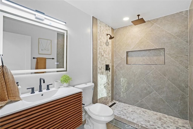 full bath featuring recessed lighting, tiled shower, toilet, and vanity