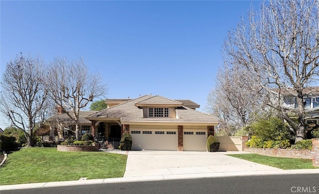 view of front facade with stucco siding, an attached garage, fence, driveway, and a front lawn