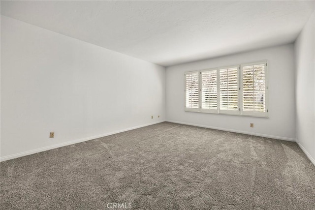 carpeted spare room featuring baseboards