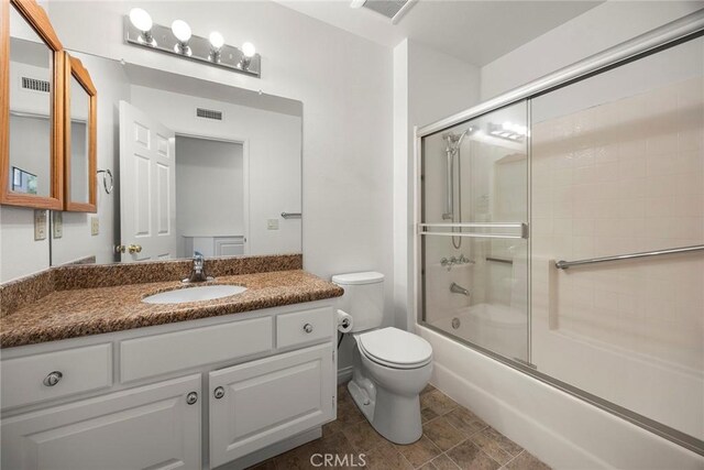 full bath with toilet, shower / bath combination with glass door, and visible vents