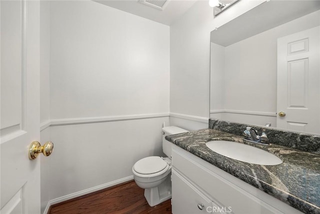 bathroom featuring baseboards, visible vents, toilet, wood finished floors, and vanity