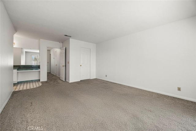 unfurnished living room with carpet, visible vents, and baseboards