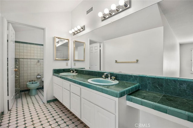 full bathroom with double vanity, a sink, visible vents, and tile walls