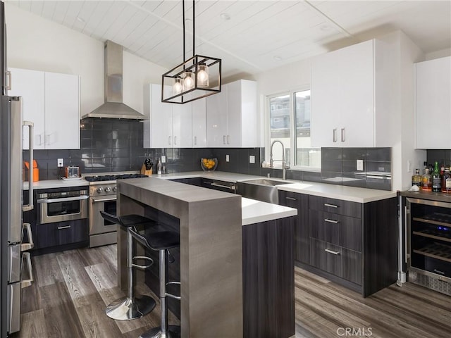 kitchen featuring a center island, stainless steel appliances, a sink, beverage cooler, and wall chimney exhaust hood