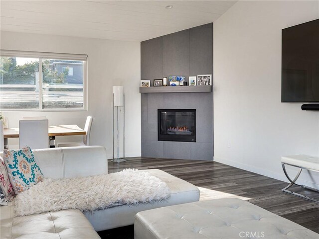 living room featuring a fireplace, baseboards, and wood finished floors