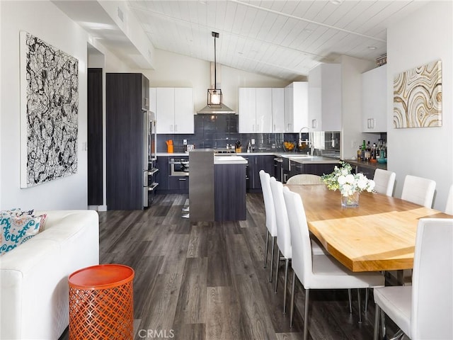 kitchen with a kitchen island, white cabinetry, vaulted ceiling, decorative backsplash, and dark wood finished floors