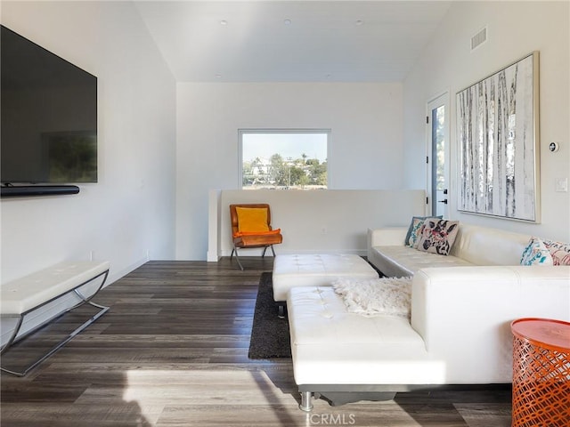 living area with lofted ceiling, visible vents, plenty of natural light, and wood finished floors