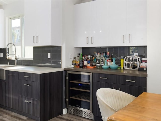 kitchen with beverage cooler, a sink, white cabinets, decorative backsplash, and modern cabinets