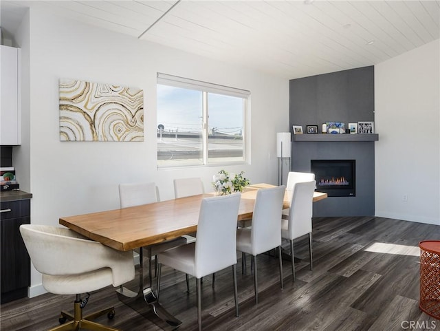 dining room featuring wooden ceiling, a fireplace, baseboards, and dark wood-type flooring