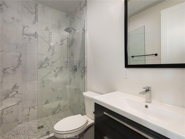 full bath with vanity, a marble finish shower, and toilet