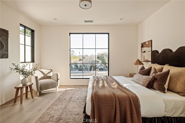 bedroom with light wood-style floors and visible vents