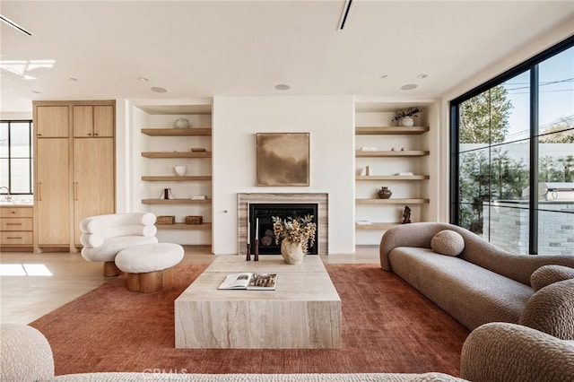 living room with a healthy amount of sunlight, built in shelves, and a fireplace